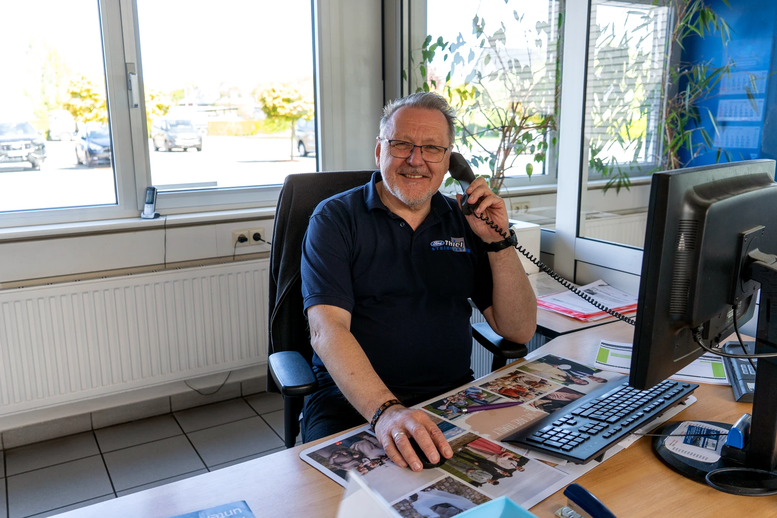 Mitarbeiter des Autocentrum Thiel telefoniert am Arbeitsplatz in Steinfurt