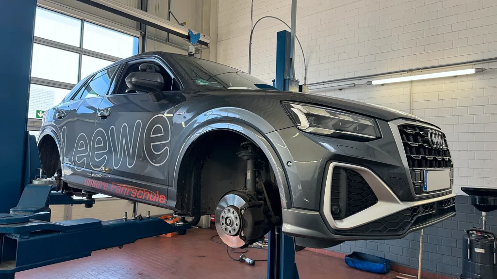 Werkstattmitarbeiter führt einen Bremsenservice an einem Audi aus.